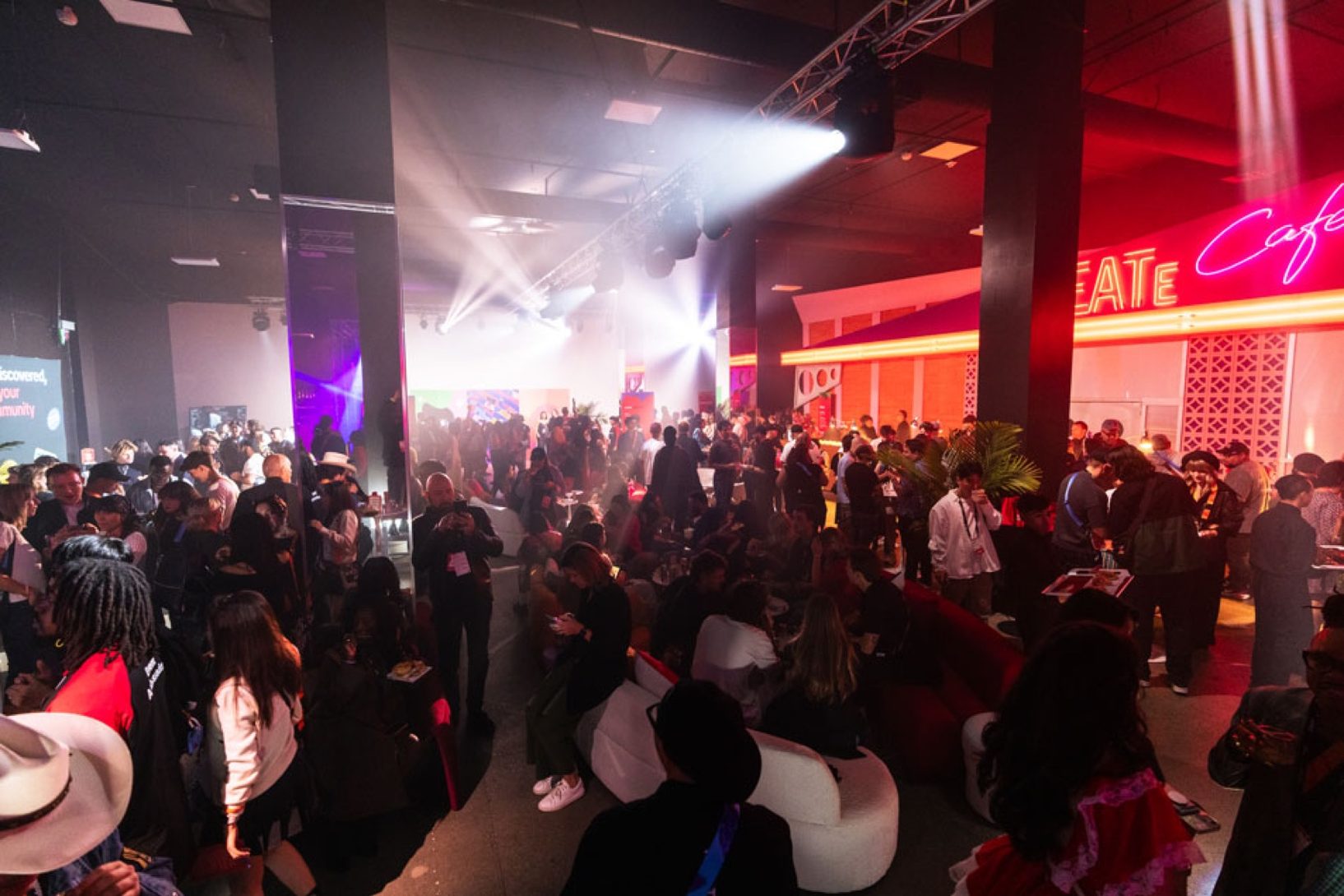 A DJ performing on stage in front of a crowd at Adobe MAX inside Magic Box